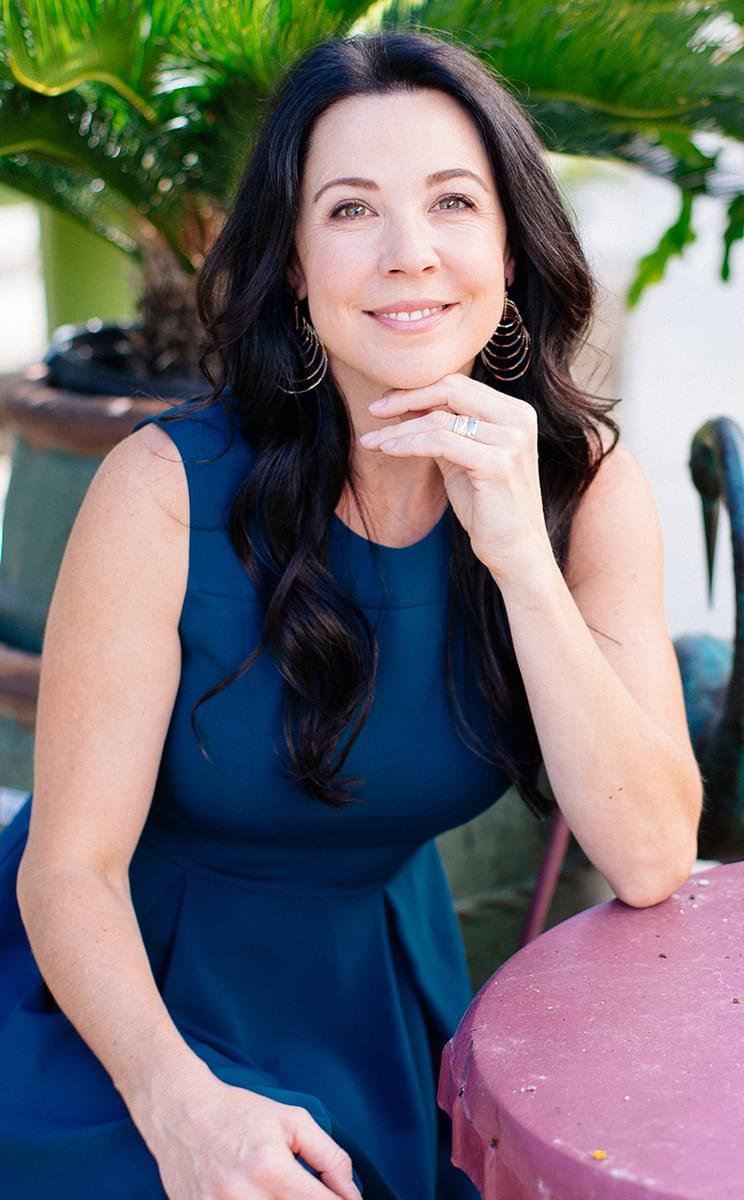 Picture of Stacy sitting at a small table, smiling at the camera.